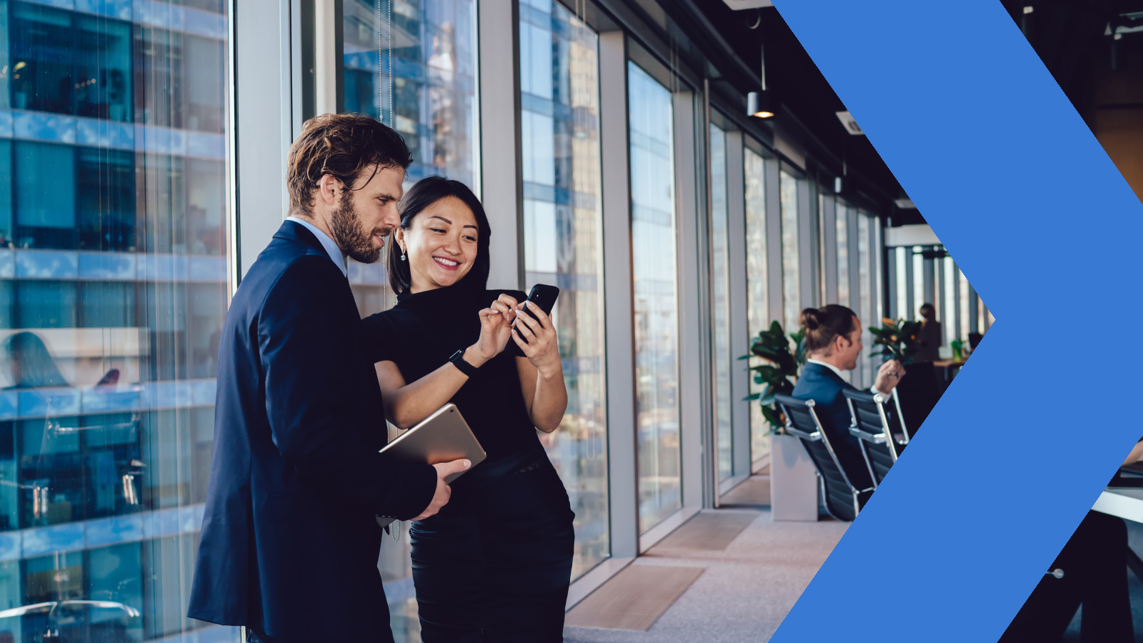 Two coworkers look at a smart phone